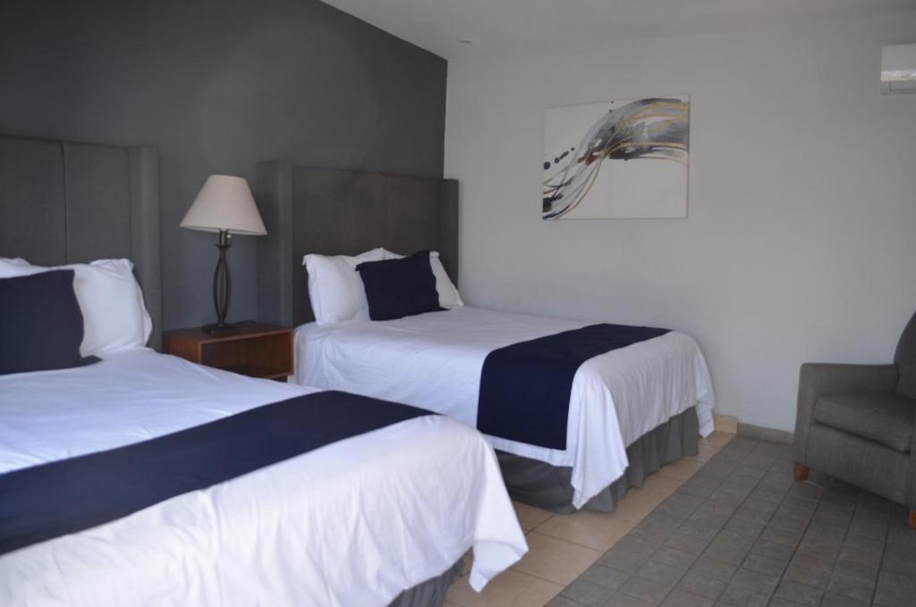 una habitación de hotel con 2 camas y una silla en Hotel CASA PETRI, en Ensenada