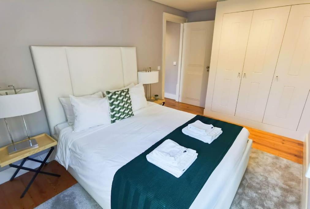 a bedroom with a white bed with a green blanket at Exuberante refúgio no centro de Lisboa in Lisbon