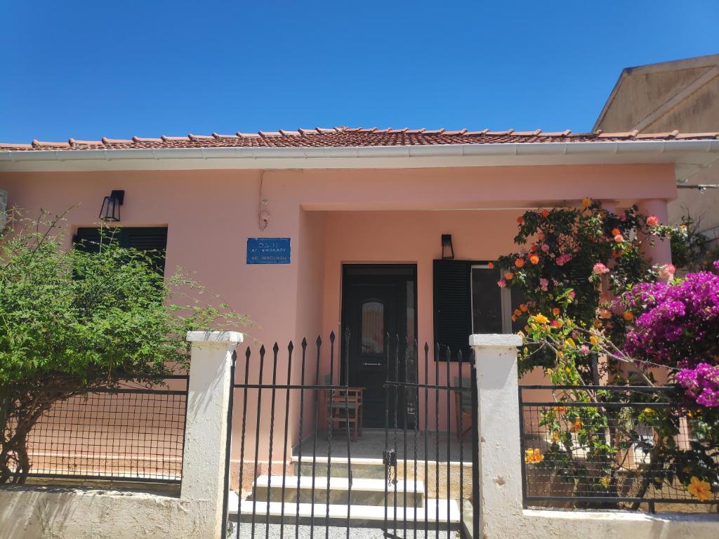 een klein roze huis met een hek en bloemen bij Το σπίτι με τις βουκαμβίλιες in Ayia Evfimia