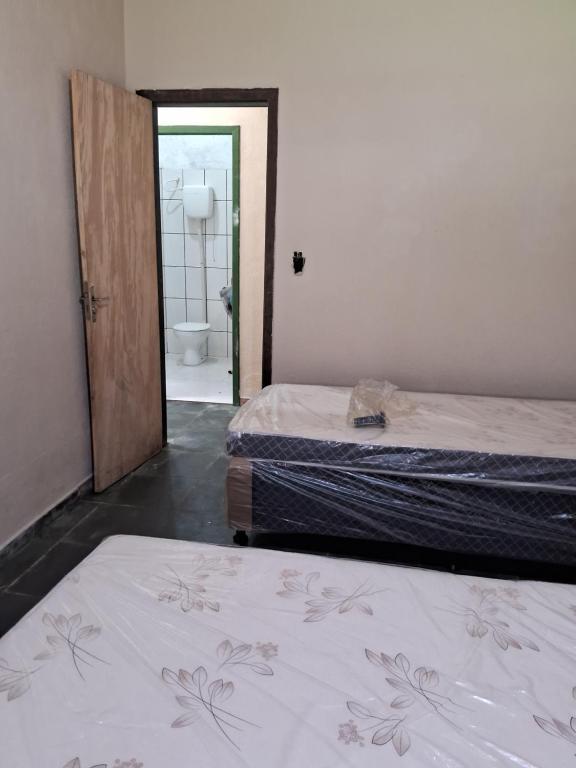 2 Betten in einem Zimmer mit Tür zum Bad in der Unterkunft Casa Laranja in Angra dos Reis