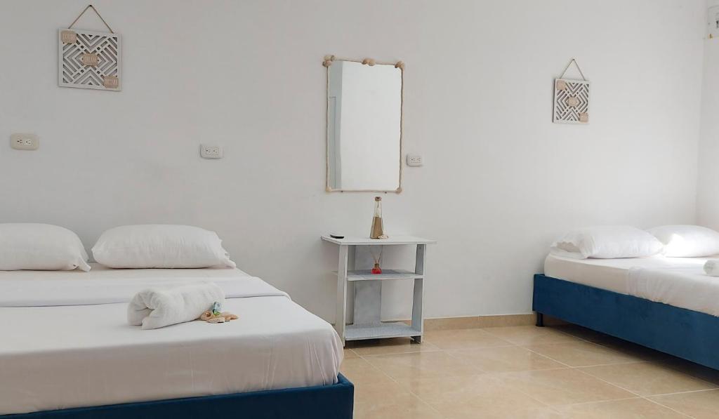 Cette chambre blanche comprend 2 lits et un miroir. dans l'établissement La Marina Hostal, à Ríohacha