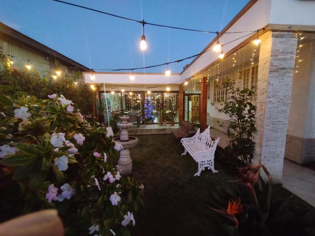 una casa con un banco blanco en un patio con flores en HOSTAL LA MODERNA, en Quintero
