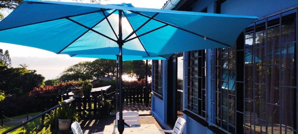 a blue umbrella on top of a porch with chairs at Thalassa's in Port Shepstone