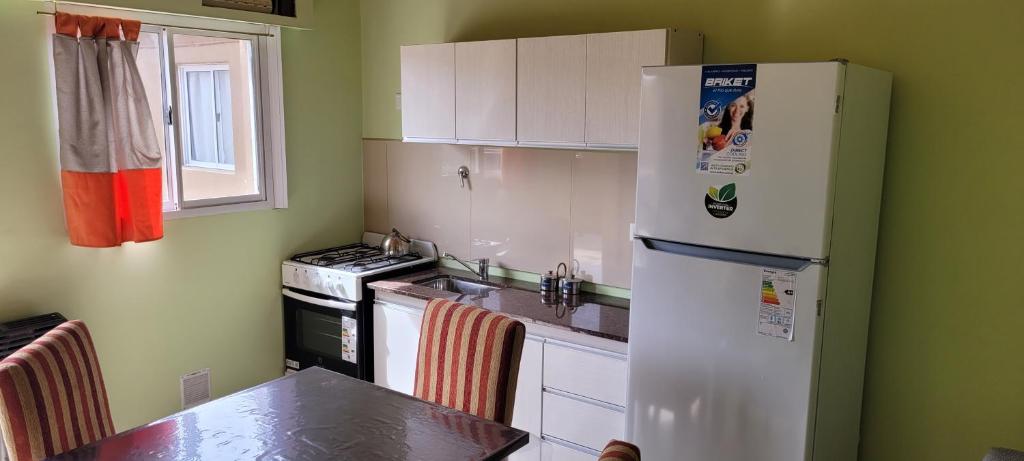 a kitchen with a white refrigerator and a table at ALQUILERES MARLUZ in Trelew