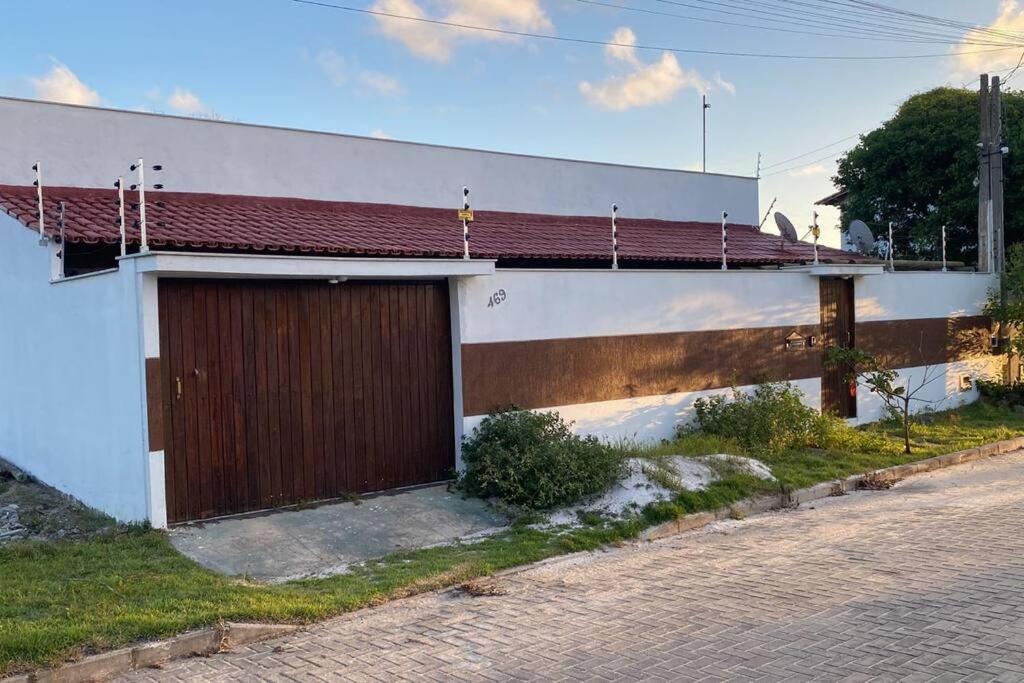 un bâtiment blanc avec une porte marron dans une rue dans l'établissement Beach House Guriri - Casa de temporada, à São Mateus
