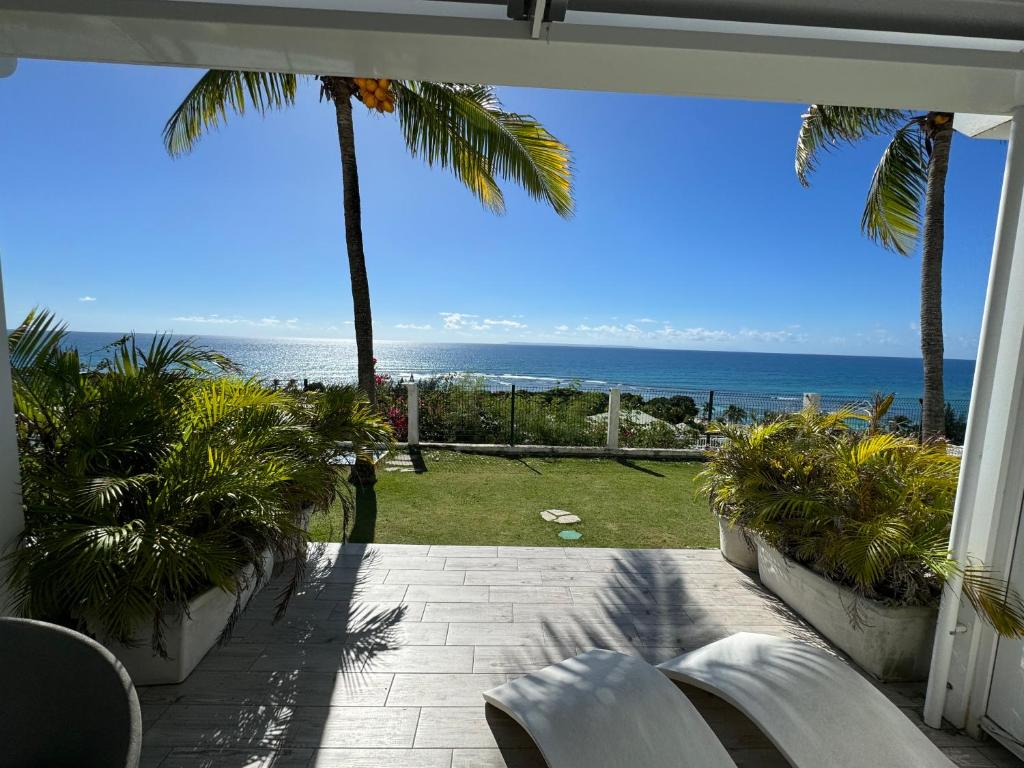 a view of the ocean from a patio with palm trees at Moana Lodge in Saint-François