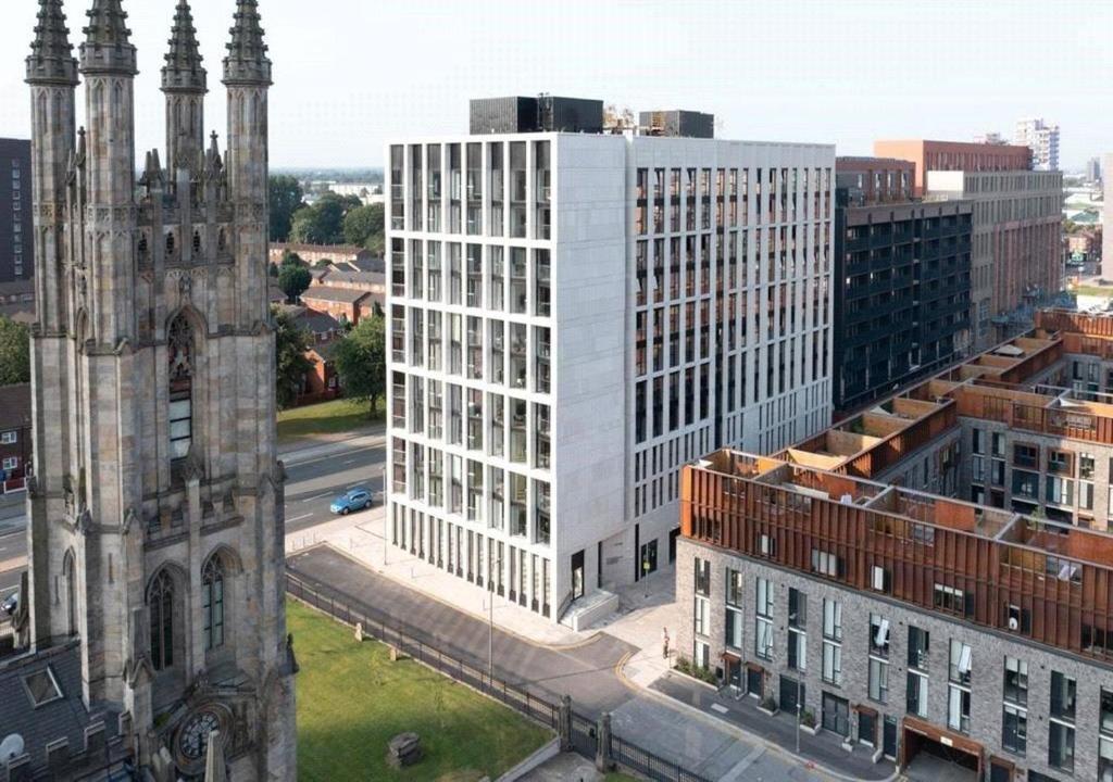 an aerial view of a tall white building next to a church at Modern 1-bed Duplex+Balcony in Manchester