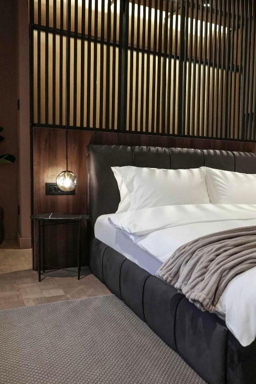 a bedroom with a bed with a black headboard and a table at ZEST Verde in Kragujevac