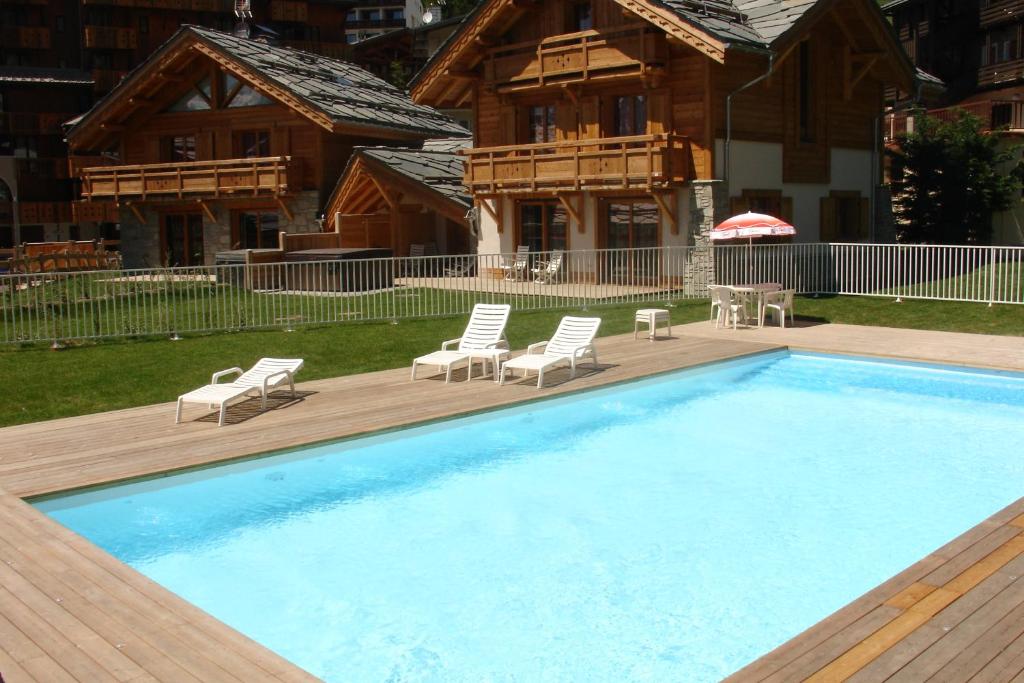 una gran piscina con sillas y una casa en Chalet Faverot 1, en Les Deux Alpes