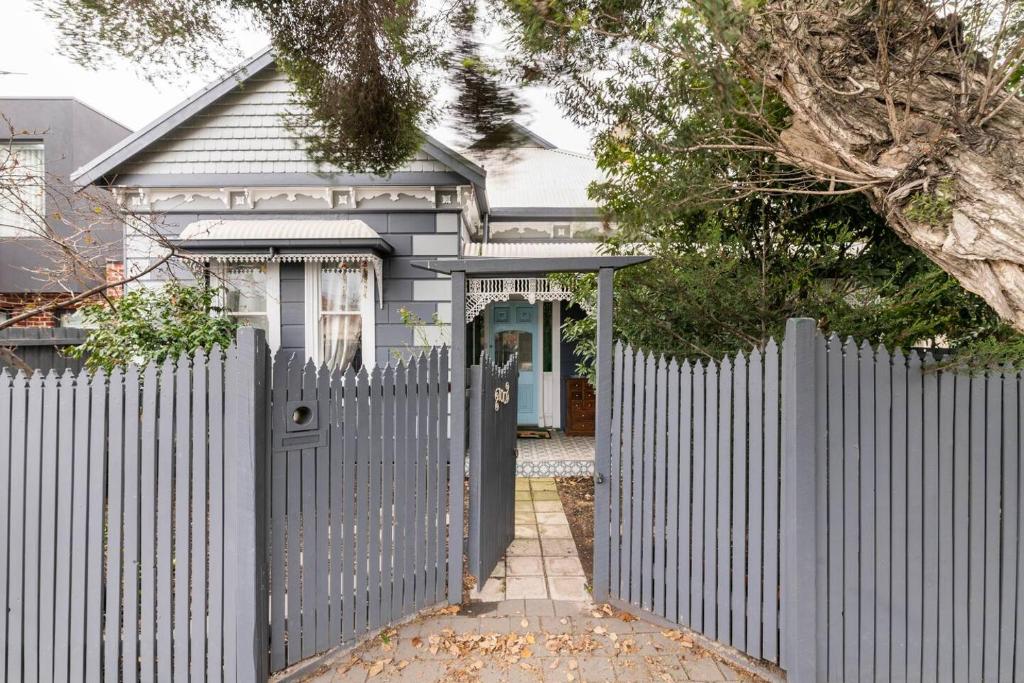 a white fence in front of a house with a gate at Urban Elegance apartment in Yarraville village in Yarraville