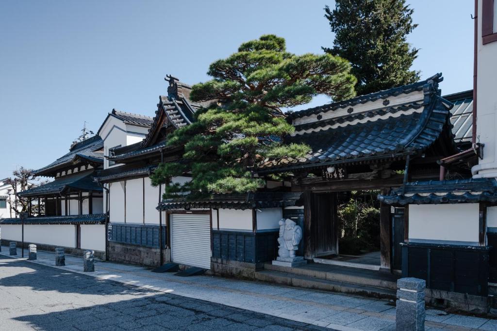 a building with a tree in the middle of a street at 信州善光寺 薬王院 in Nagano