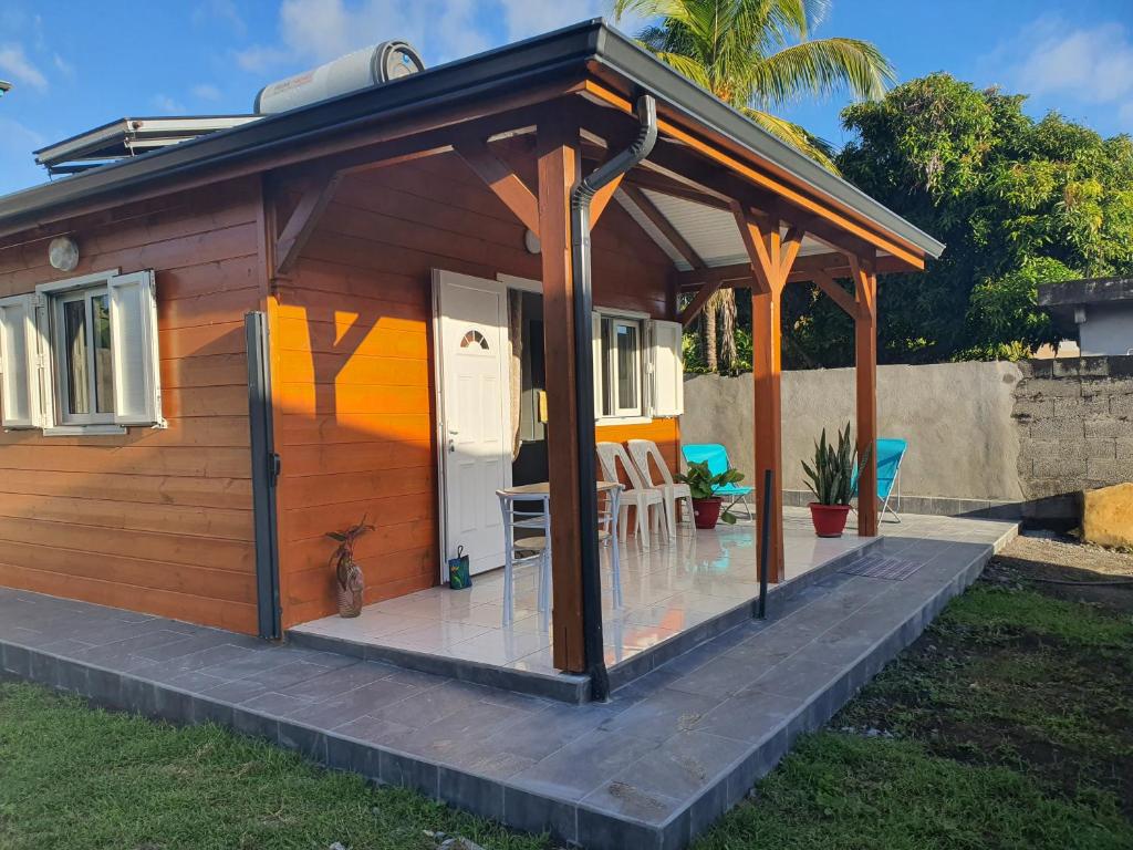 eine kleine Holzhütte mit einer Veranda und Stühlen in der Unterkunft Bungalow vacances in Sainte-Rose