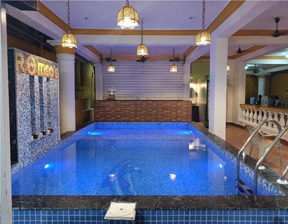 a large swimming pool with blue tile in a building at Hotel Romeo's Place Near Baga Beach - 50 meters from Baga Beach in Baga