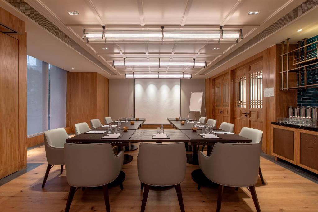 A symmetrical conference room with a large central table, screen and service counter.