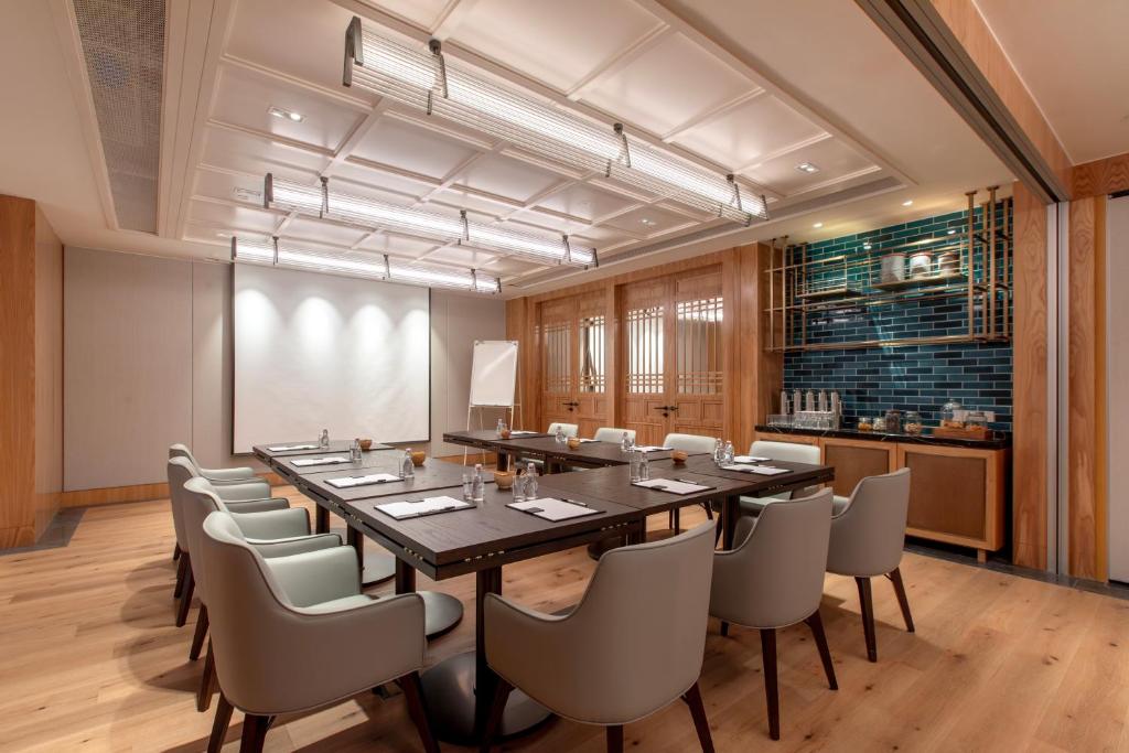 A long, formally set conference table in a wood-panelled meeting room.