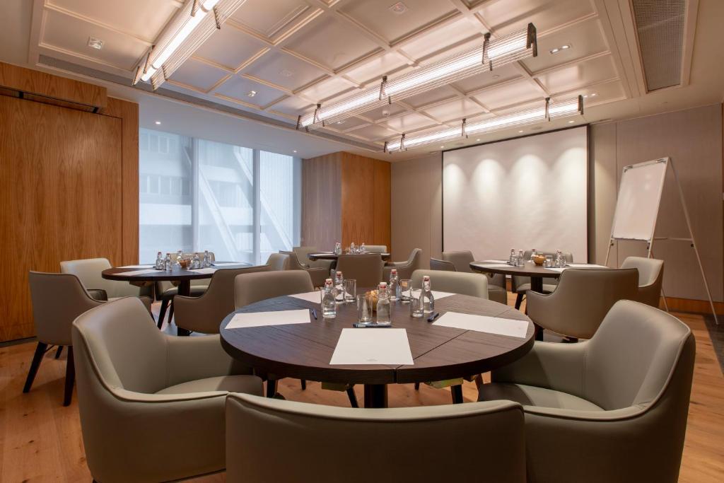 A meeting room arranged with round tables, a presentation screen and a flip chart.