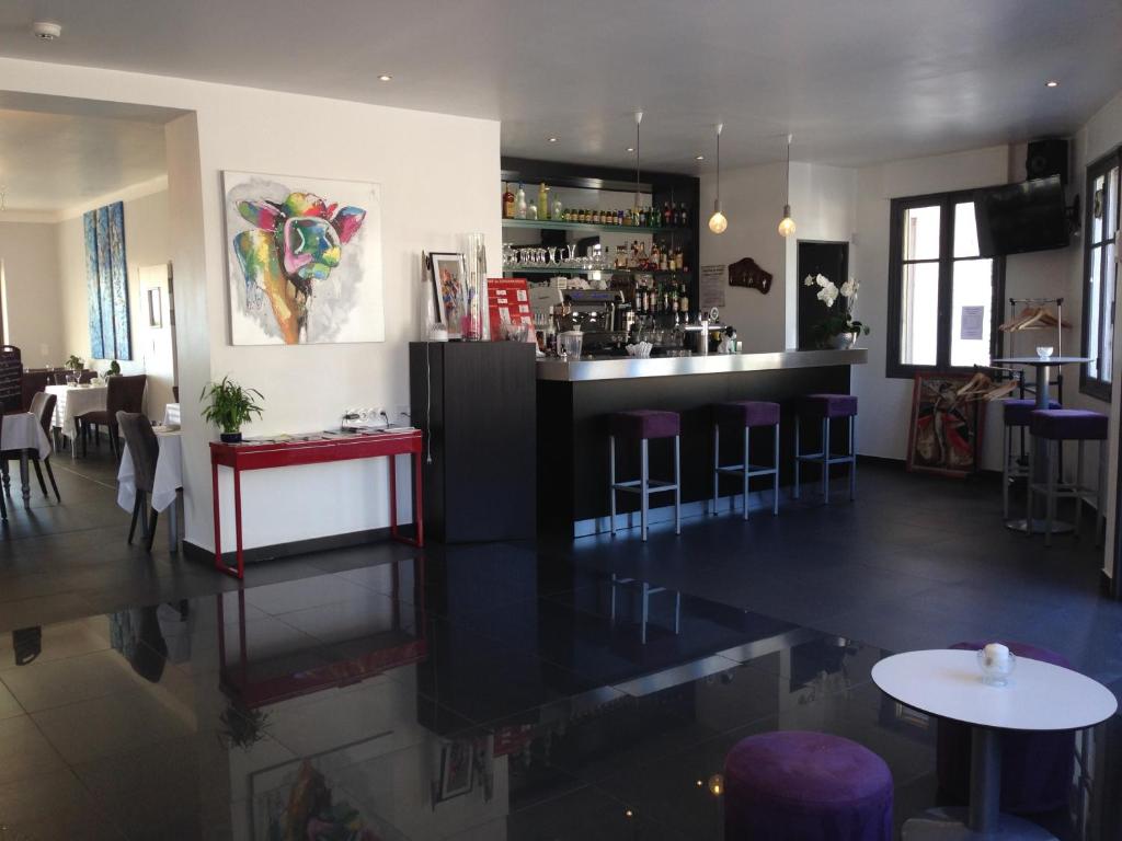 a restaurant with a bar with purple stools at Hotel La Cigale in La Croix-Valmer