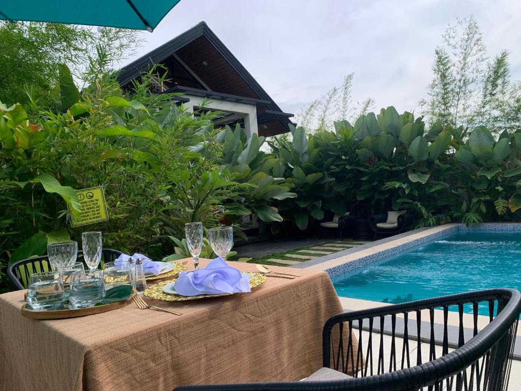 a table with wine glasses and a table cloth next to a pool at Larue Pocket Villa in Calatagan