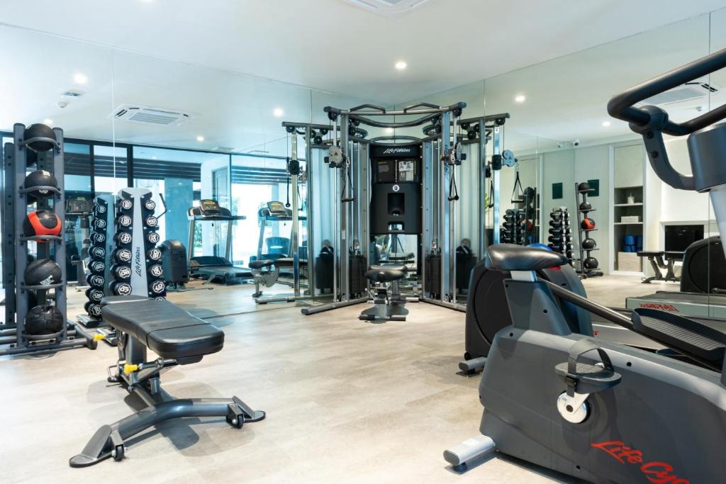 A mirrored fitness room with strength and cardio equipment.