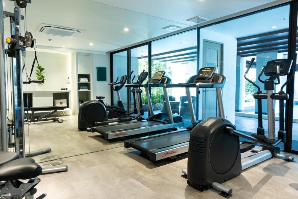 A cardio-focused gym with treadmills and ellipticals facing glazed windows.