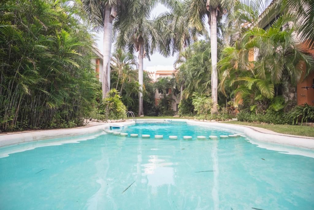 a swimming pool with palm trees in a resort at Casa Serena in Cancún