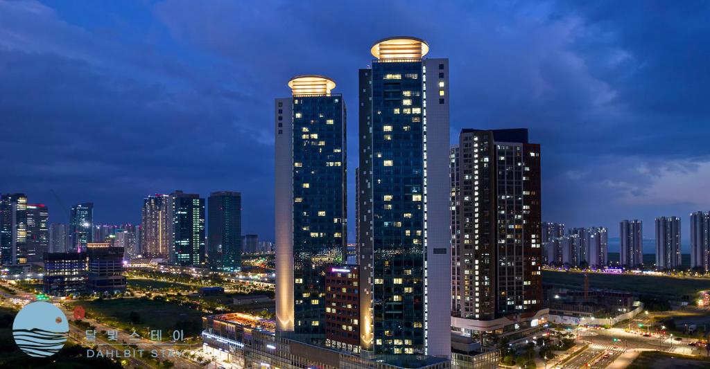 un perfil urbano con rascacielos altos por la noche en Dahlbit stay, en Incheon