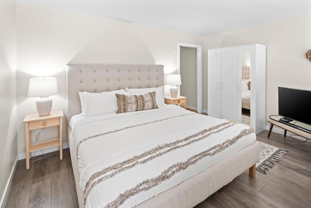 1 dormitorio blanco con 1 cama grande y TV en Trendy 3 bedroom Loft in Chinatown with Parking!, en Victoria