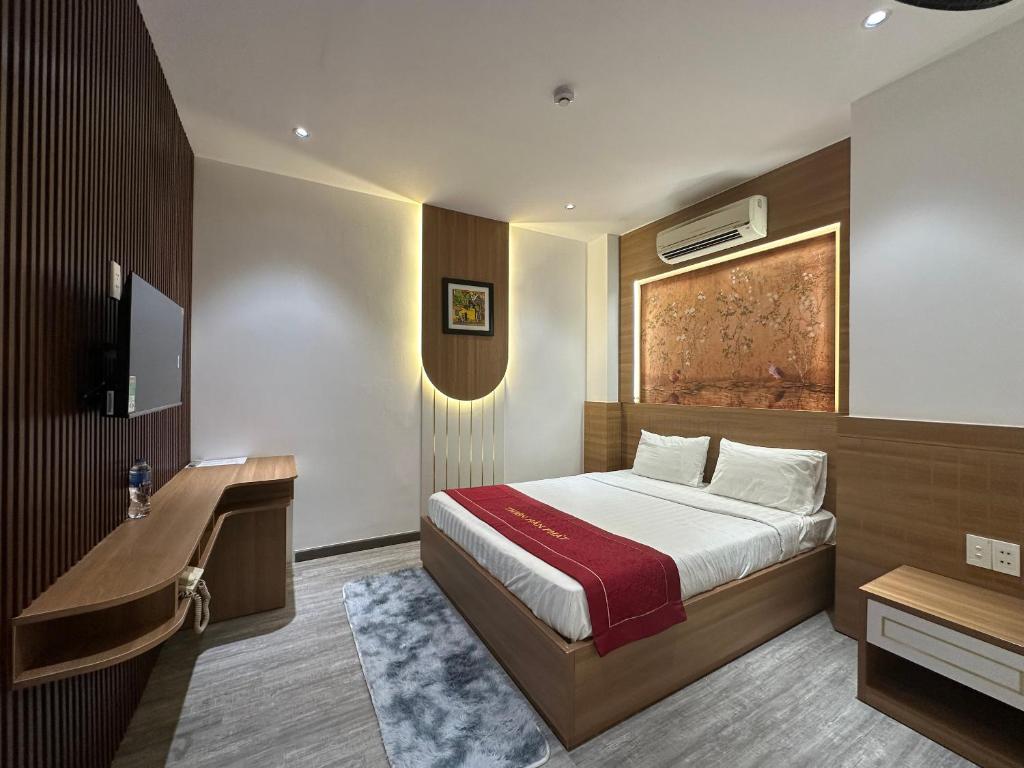 um quarto com uma cama, uma secretária e uma televisão em OYO 1219 Thien Han Phat Hotel em Da Nang