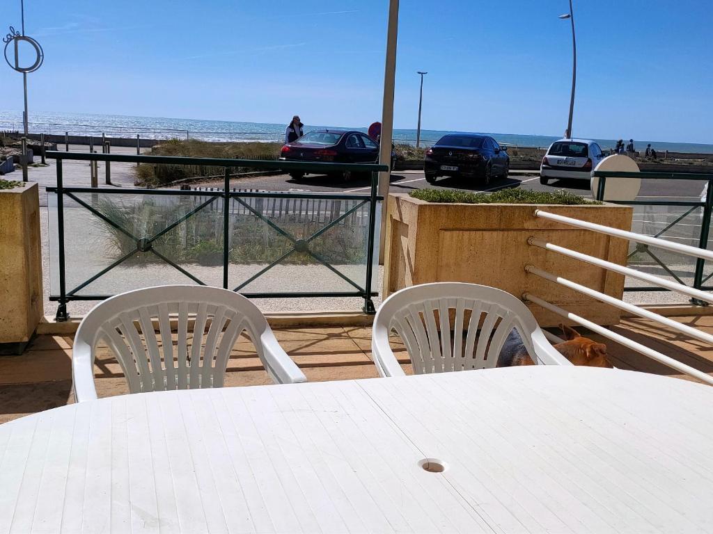 - une table et des chaises blanches avec vue sur la plage dans l'établissement Appartement Front de Mer avec Terrasse, Proche École de Voile - 4 Pers, Saint-Hilaire-de-Riez - FR-1-323-455, à Saint-Hilaire-de-Riez