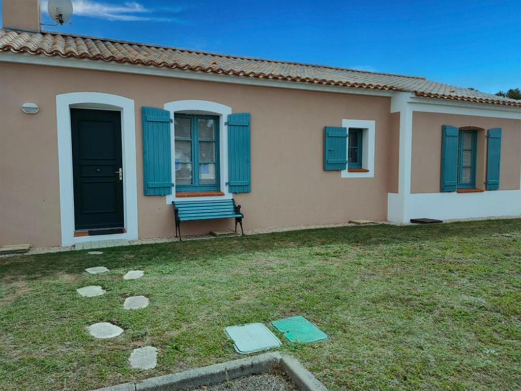 une maison avec des fenêtres bleues et un banc dans une cour dans l'établissement Maison avec 2 chambres, piscine privée et jardin clos à Saint-Jean-de-Monts - FR-1-323-439, à Saint-Jean-de-Monts