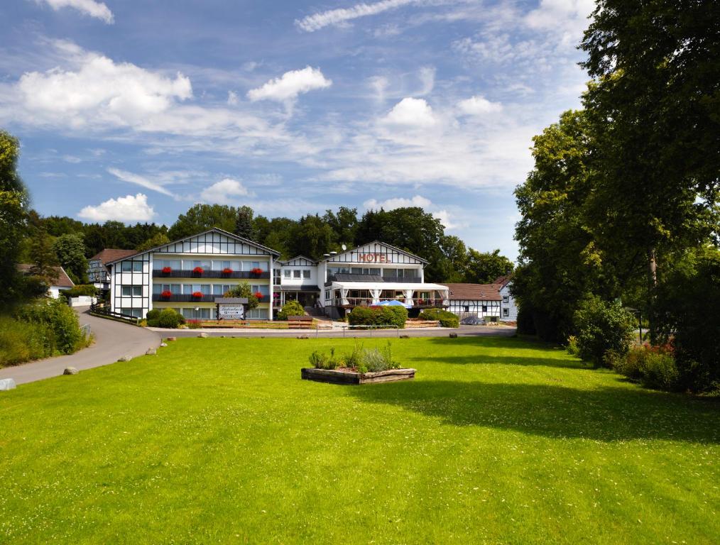 einen großen grünen Hof mit Gebäuden im Hintergrund in der Unterkunft Hotel Restaurant Lüdenbach in Overath