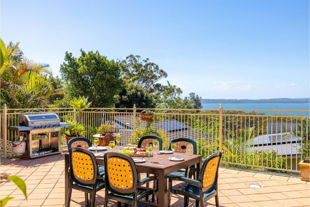 - une table et des chaises sur une terrasse donnant sur l'océan dans l'établissement Casa Carinho, 24 Wallawa Rd - spectacular water views, pet friendly, air con and Wi-Fi, à Nelson Bay