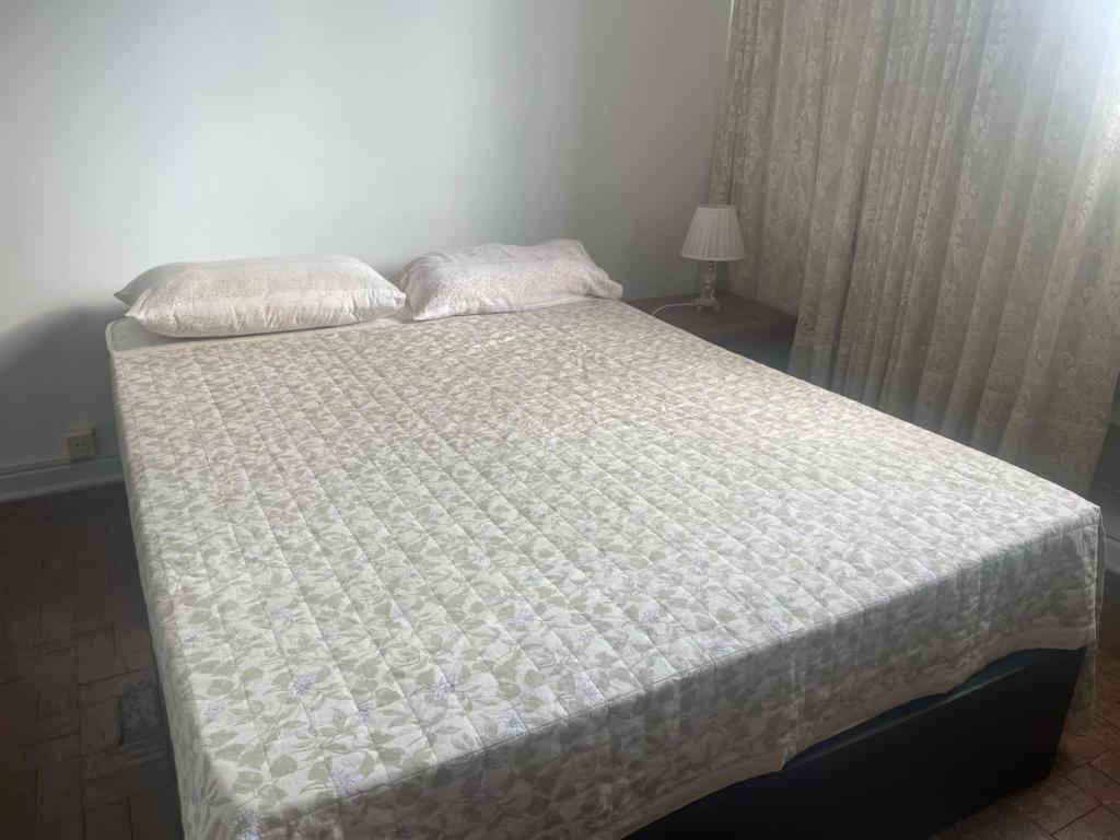a bed in a bedroom with a white bedspread and pillows at Quarto em apartamento in São Paulo