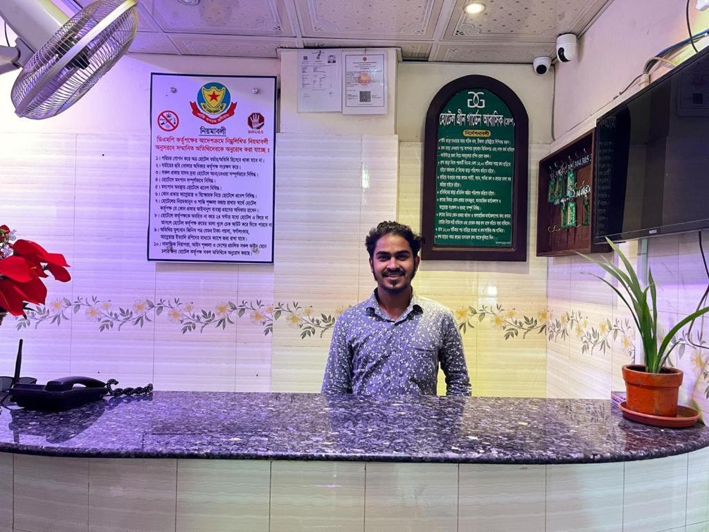a man standing behind a counter in a restaurant at Hotel Green Garden Residential Jatrabari in Dhaka