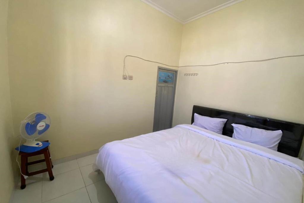um quarto com uma cama, uma cadeira e uma ventoinha em SPOT ON 93452 Wulan Homestay 2 Syariah em Tegal