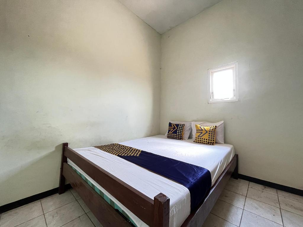 ein Schlafzimmer mit einem Bett in einem Zimmer mit einem Fenster in der Unterkunft SPOT ON 93423 Kost Berkah in Lawang