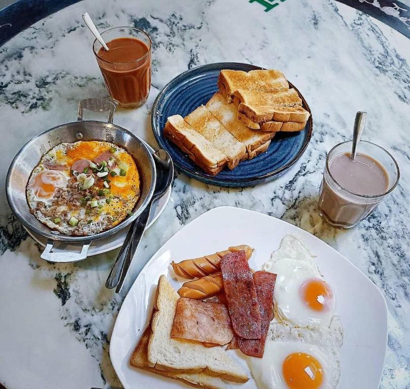- une table avec une assiette de nourriture pour le petit-déjeuner et du pain grillé dans l'établissement SUNZI BOUTIQUE HOSTEL : ซันซิ บูทีค โฮสเทล, à Betong