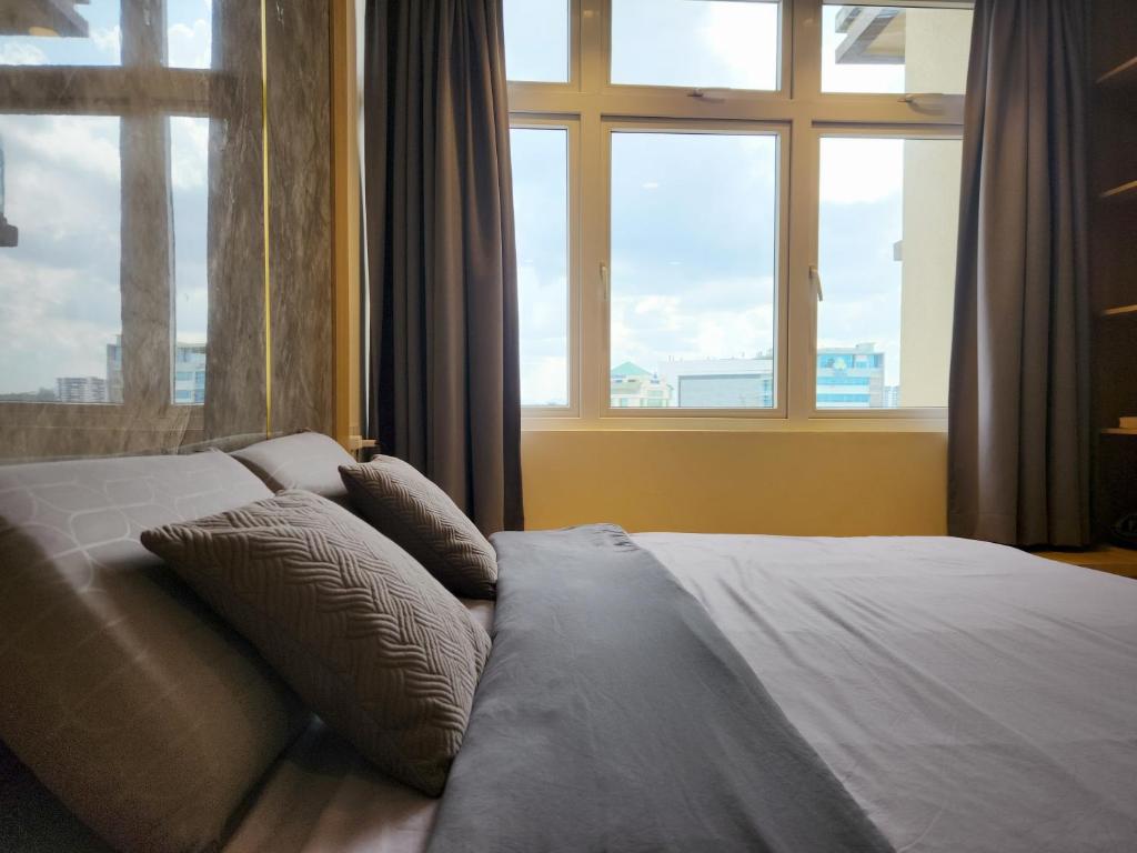 een bed met kussens in een kamer met ramen bij Kuching City Centre Smart Home Luxury Resort Condo in Kuching