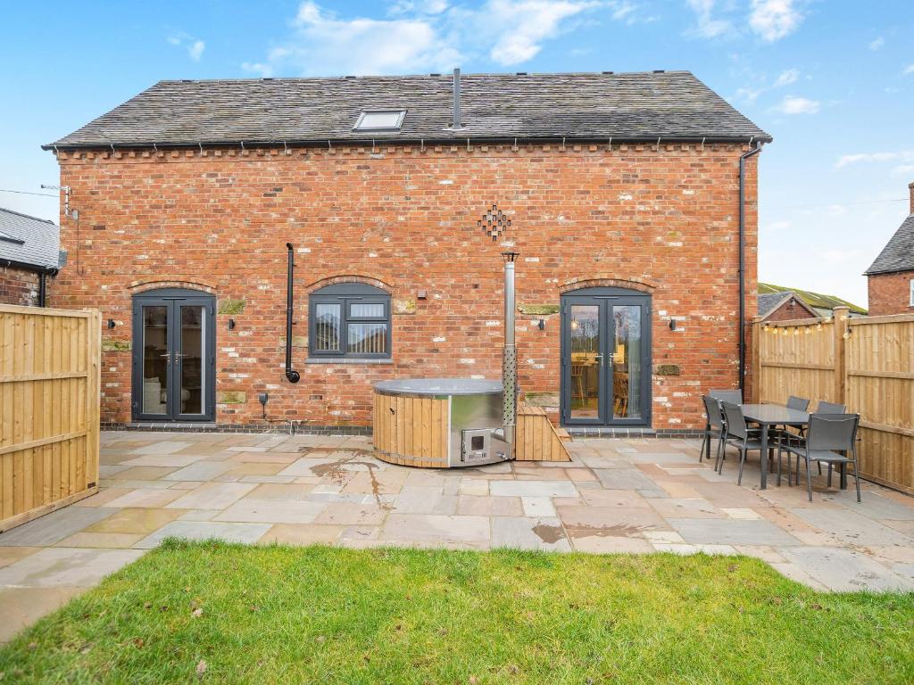 a brick house with a patio and a table at Babbling Brook Barn in Abbots Bromley