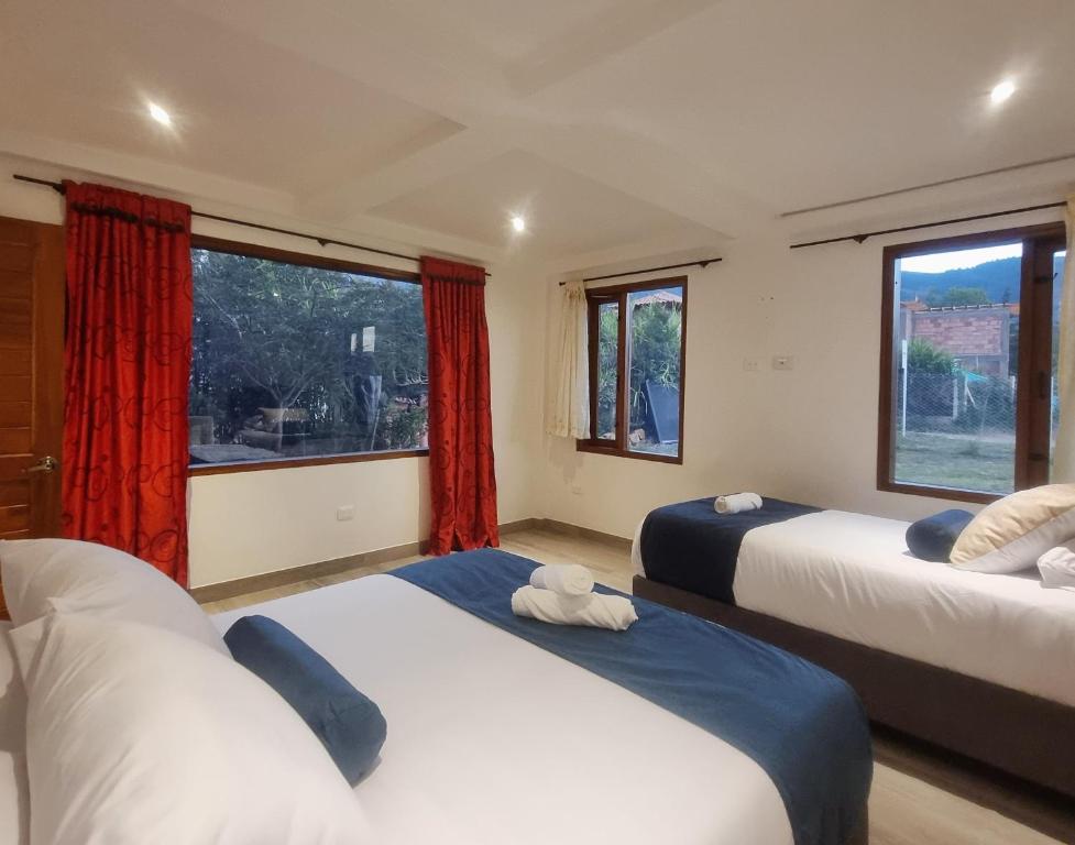 twee bedden in een kamer met twee ramen bij El Bosque de la Villa Loft in Villa de Leyva