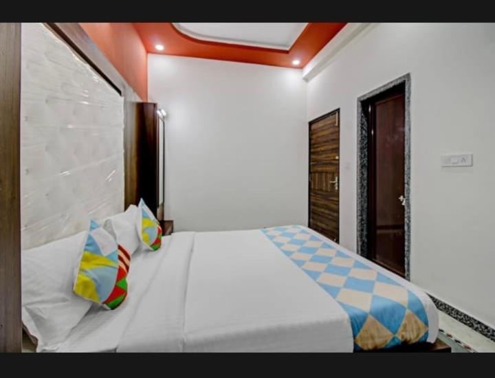 7horses holidays homes في أودايبور: غرفة نوم مع سرير أبيض مع وسائد ملونة