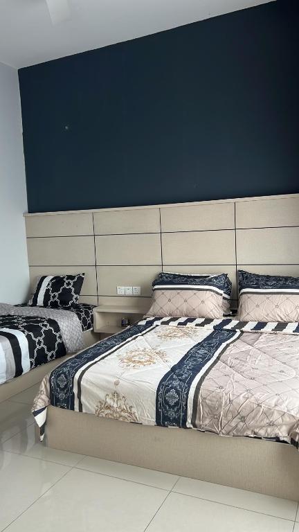 um quarto com 2 camas e uma parede azul em MV Suite Homestay em Kuantan