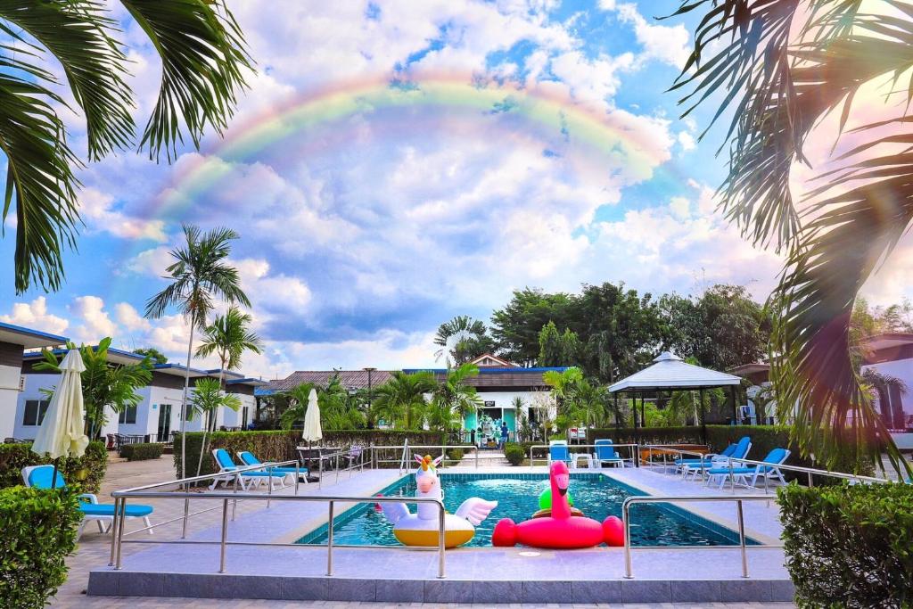 una piscina con un arco iris en el cielo en Billabong Golf Club & Resort en Nong Prue