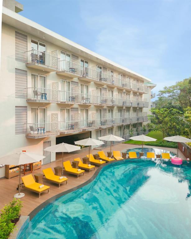 un hotel con piscina, sillas y sombrillas en ibis Styles Goa Vagator - An Accor Brand, en Vagator