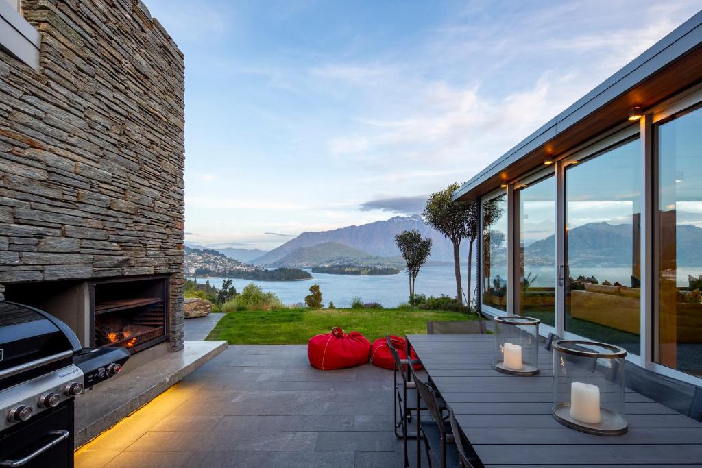a house with a patio with a view of the water at Amaroo in Queenstown