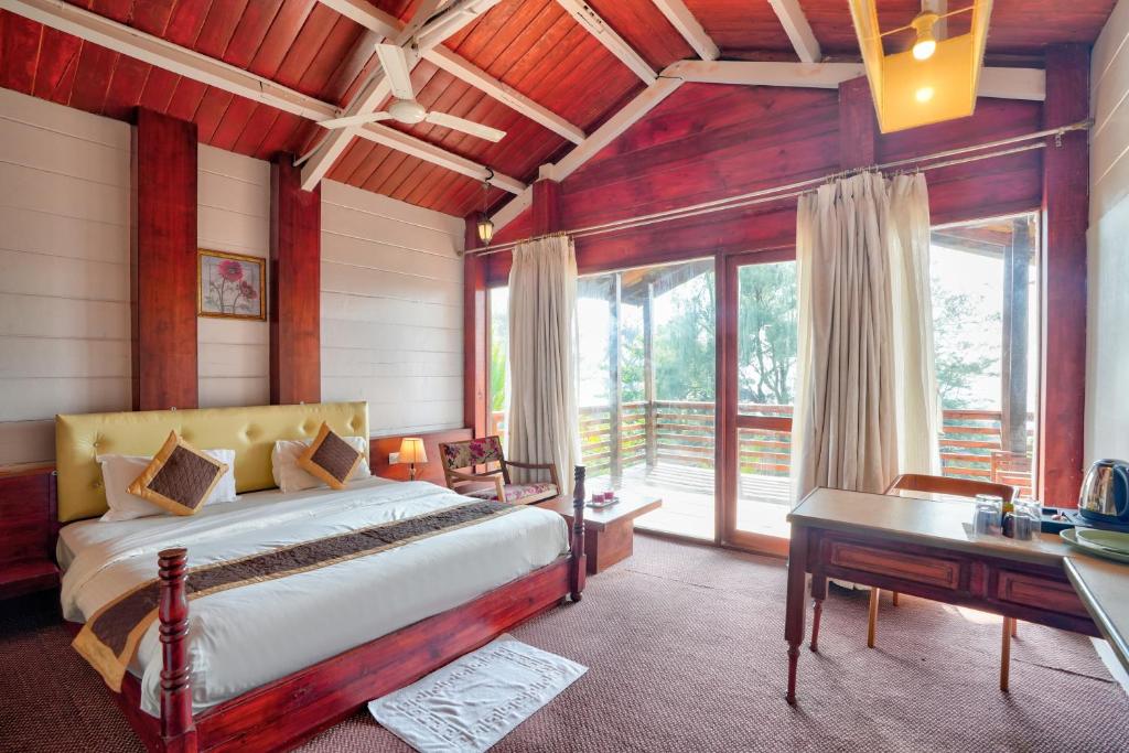 a bedroom with a bed and a desk and windows at Aqua Marina Beach Cottages in Calangute