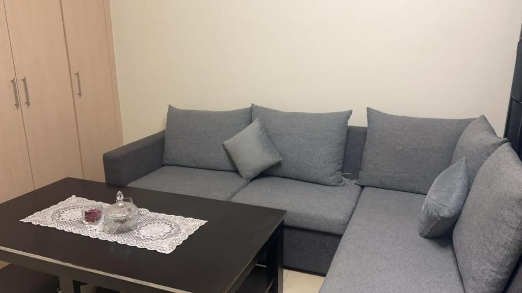 a living room with a gray couch and a table at Al badaa in Dubai