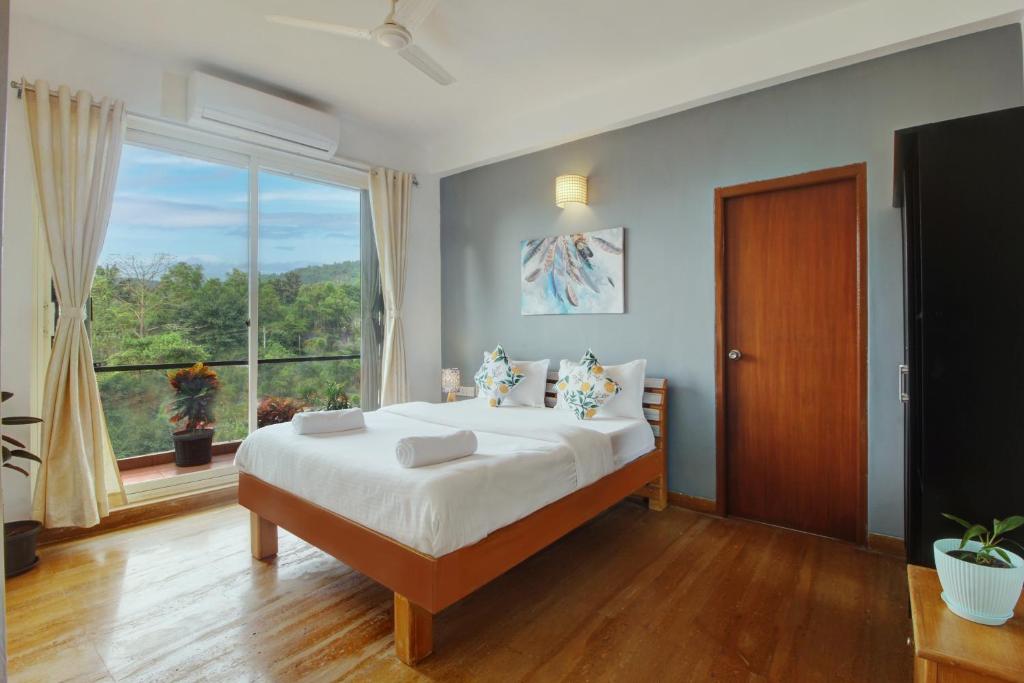Genesis Leisure - Charming home-stays near Anjuna, Vagator & Assagao في أنجونا: غرفة نوم بسرير كبير ونافذة كبيرة