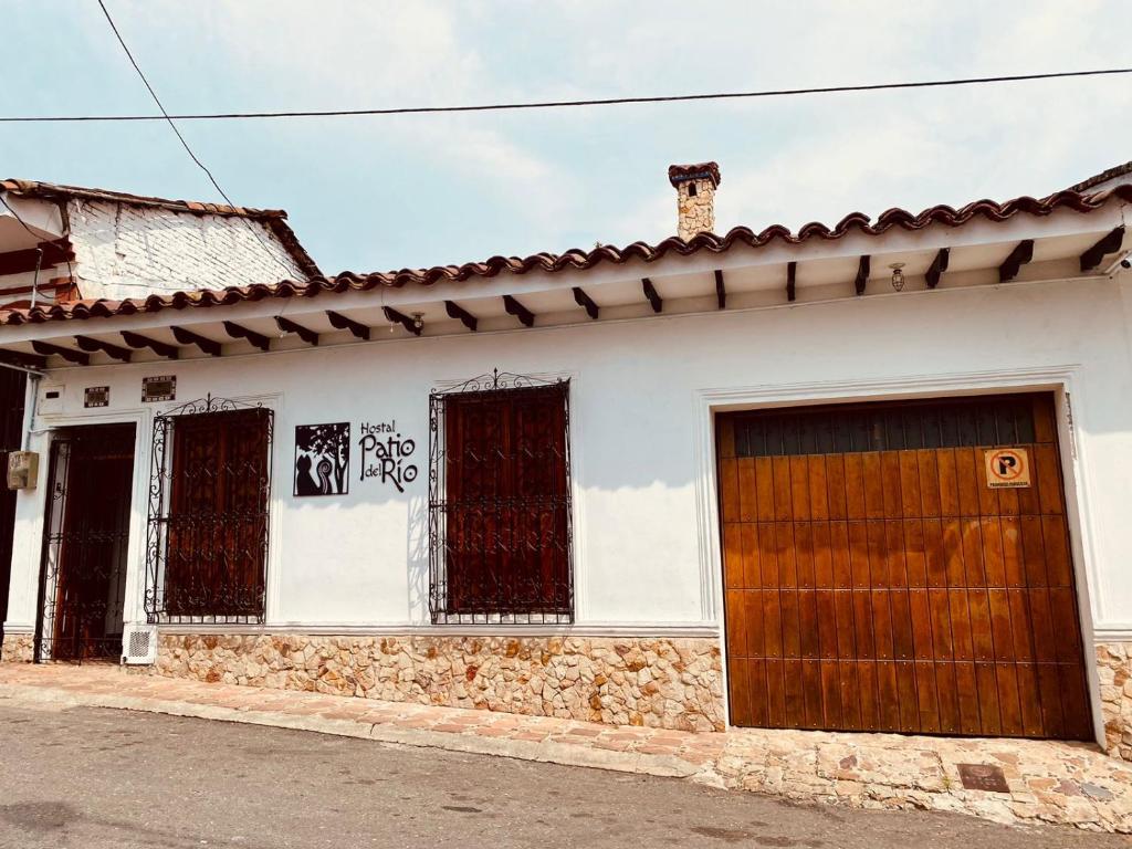 un edificio blanco con una puerta y ventanas marrones en Hostal Patio del Río, en Cali