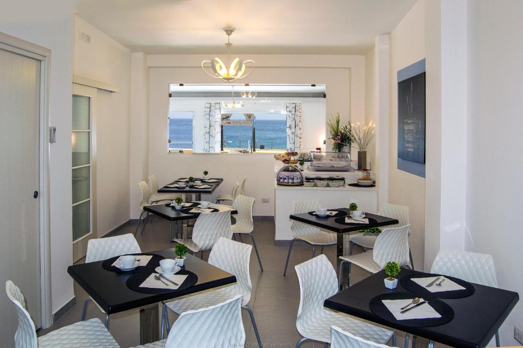 a dining room with tables and white chairs at Maniel Beach Hotel in Letojanni